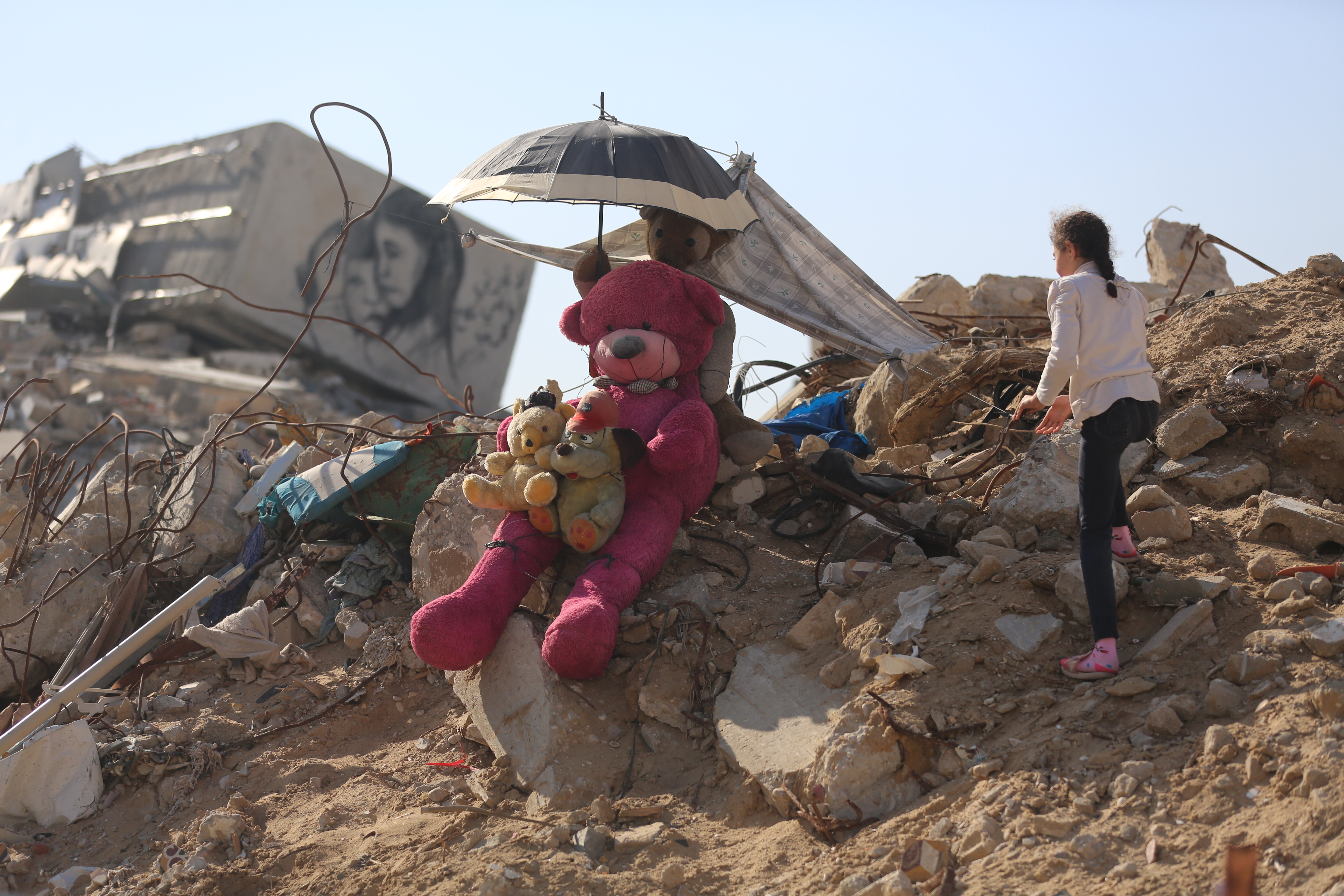 Ein Mädchen und ihr Kuscheltier in den Trümmern in Gaza