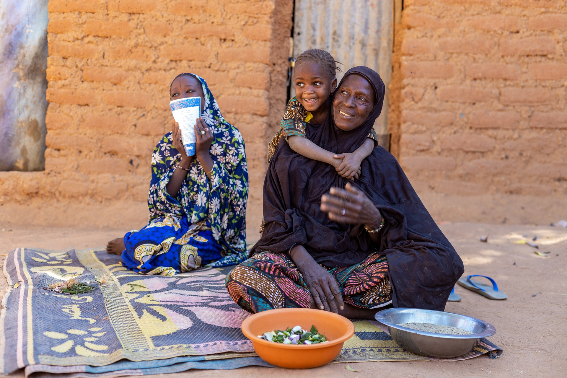 Eine Frau und zwei Kinder sitzen auf einer Decke.
