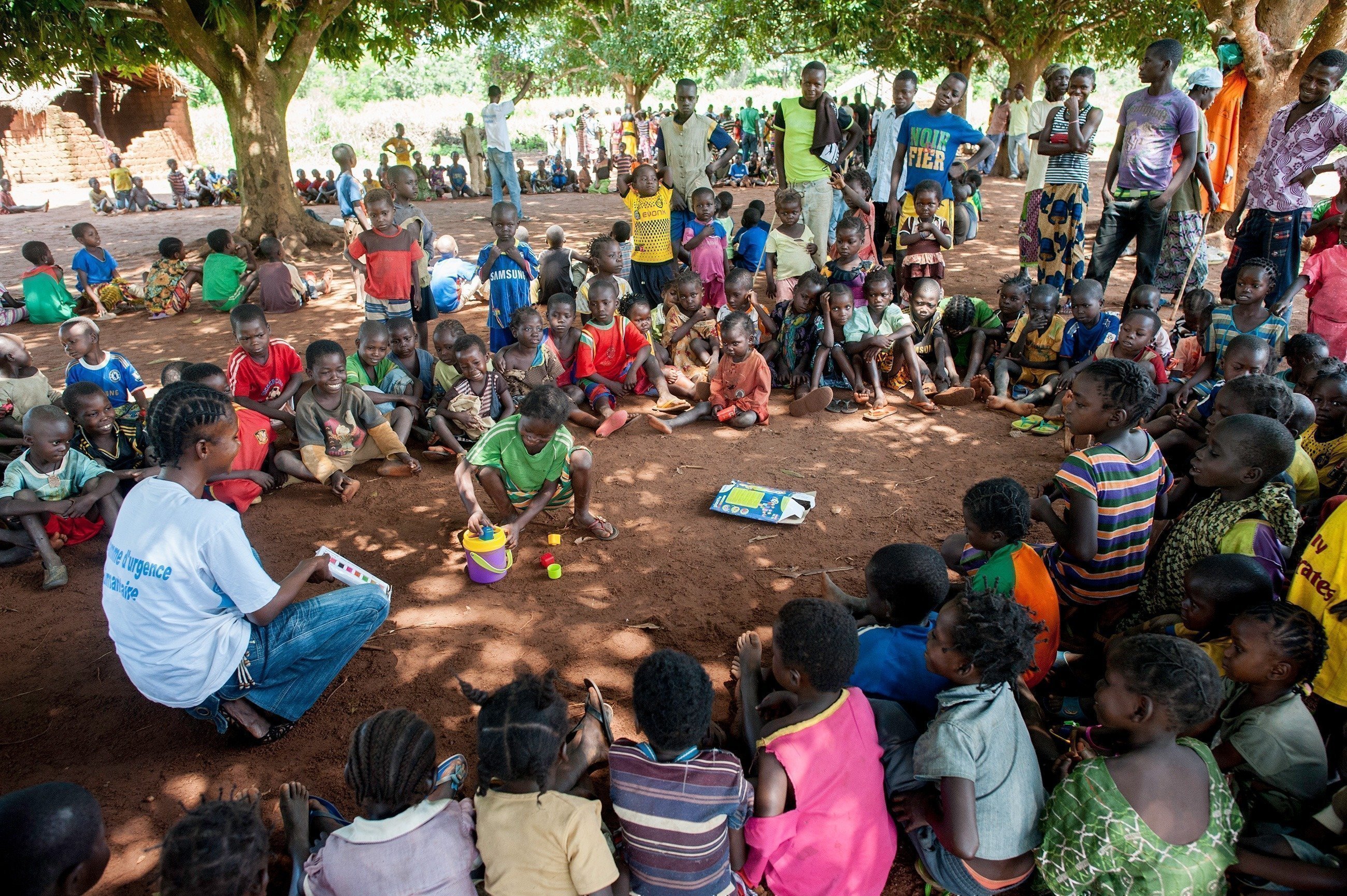 Bambini seduti in cerchio con l’assistente di SOS Villaggi dei Bambini.