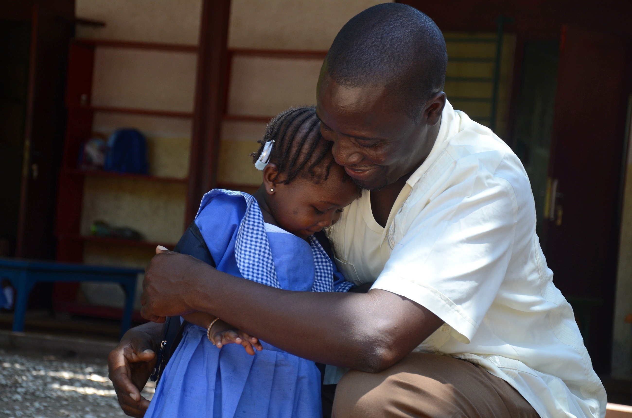 SOS-Kinderdorf Vater umarmt kleines Mädchen herzlich.