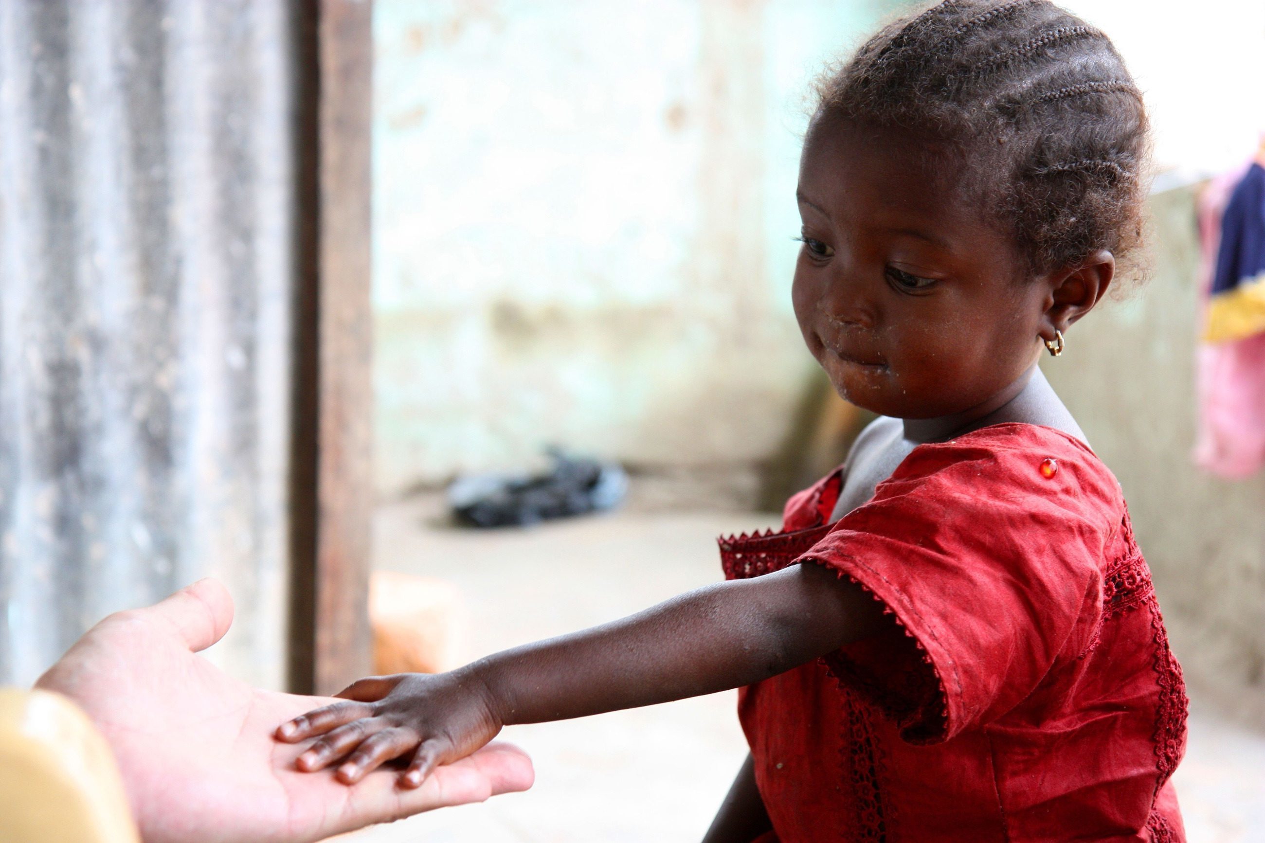 Una bambina africana tende la mano a un padrino.