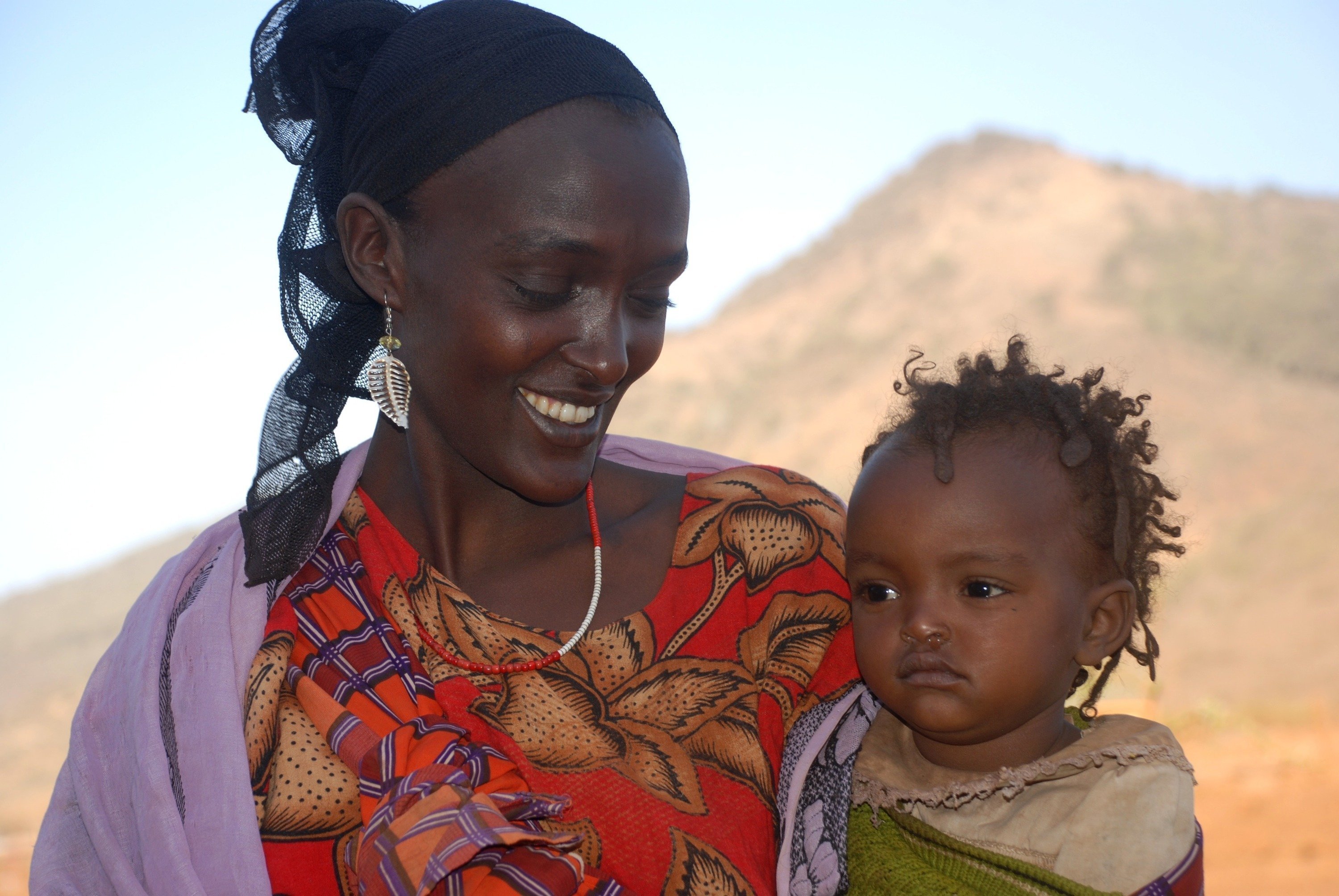 Eine SOS Kinderdorf Mutter mit einem Kleinkind auf dem Arm.