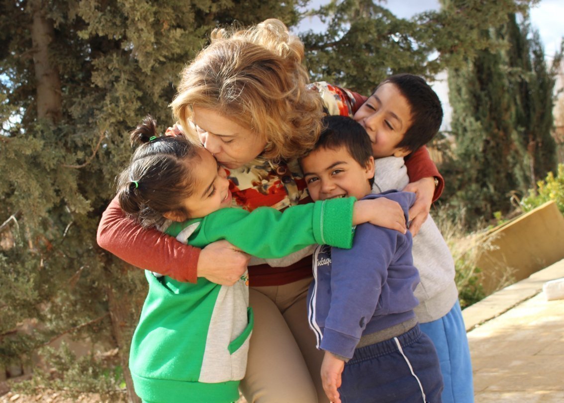 Collaboratrice SOS Villaggi dei Bambini abbraccia tre bambini