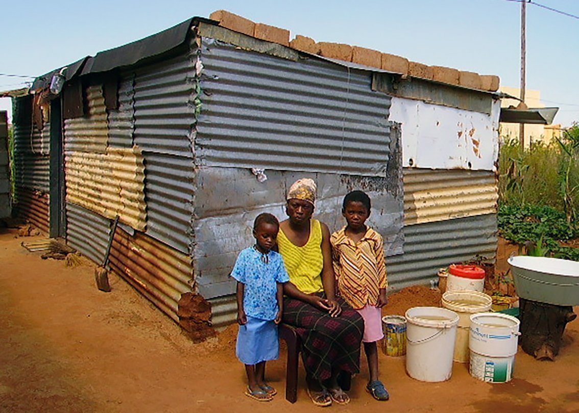 Mamma e due figli africani davanti a baracca