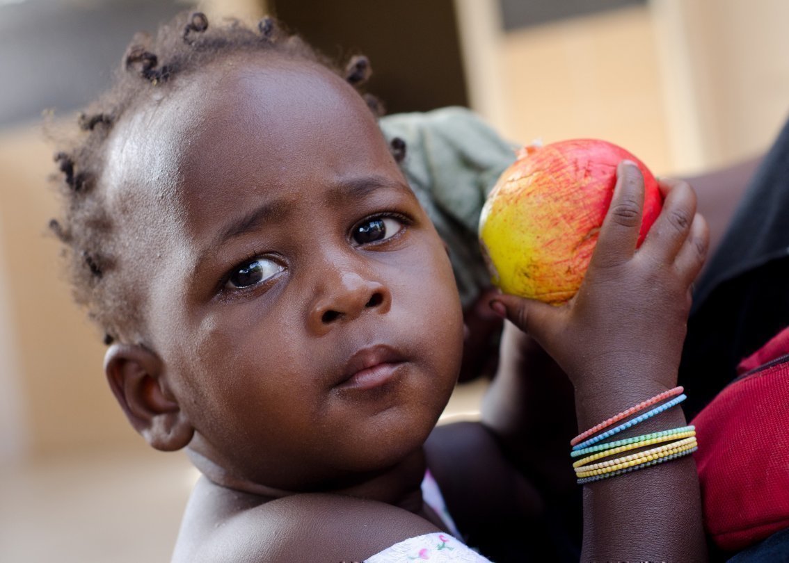 Bambina africana con in mano una mela.