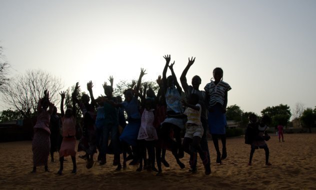 Un gruppo di bambini salta in alto sullo sfondo del tramonto.