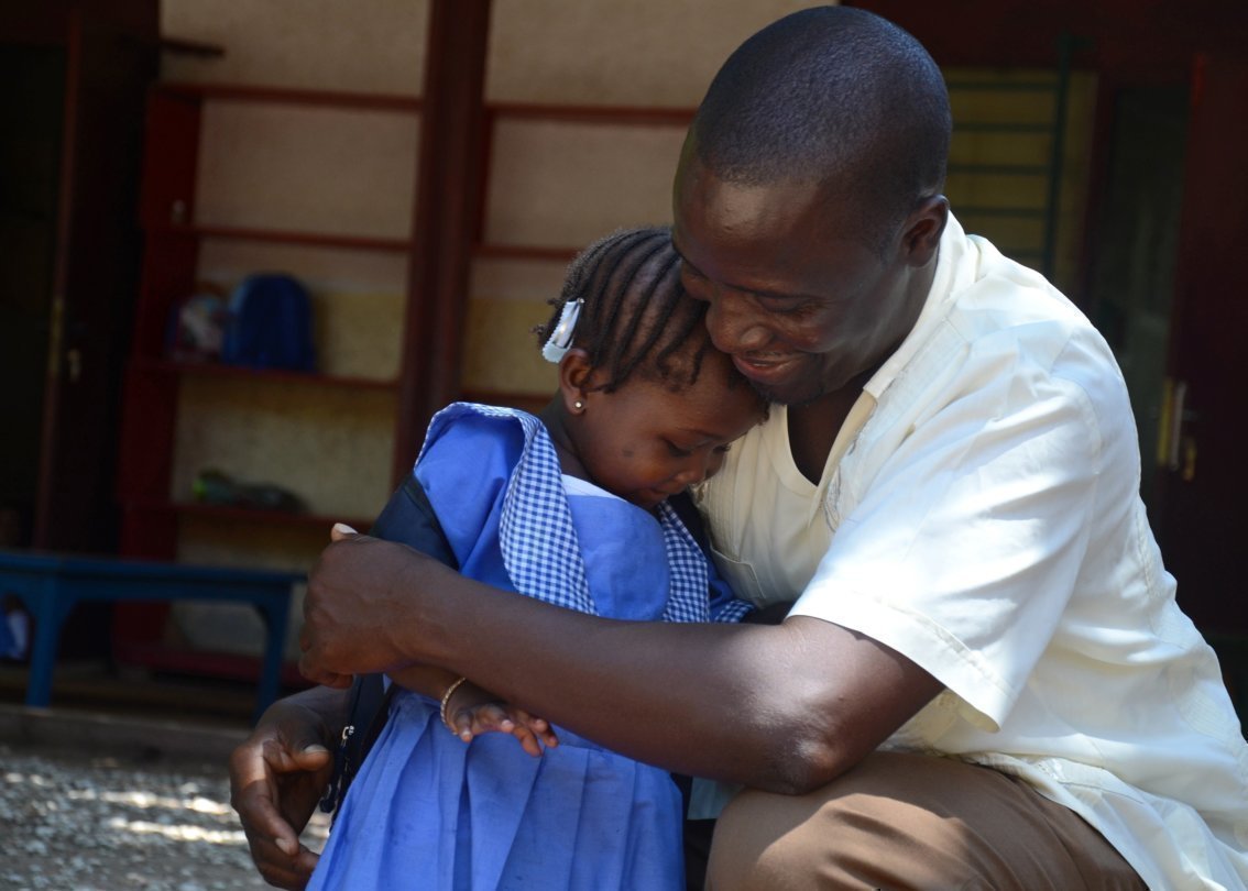 Un padre SOS abbraccia calorosamente una bambina.