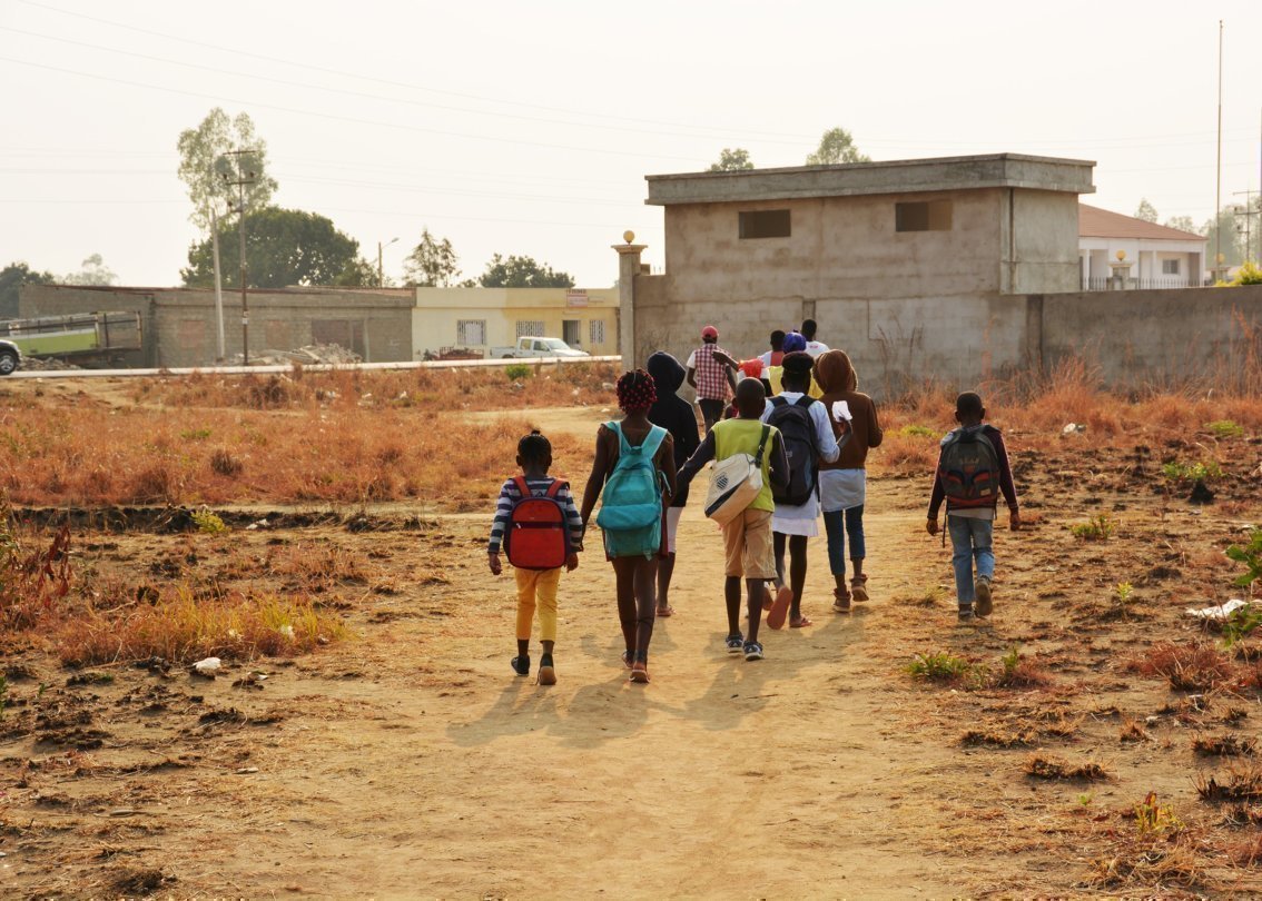 Alcuni bambini con zaino in spalla che si stanno dirigendo verso l’edificio scolastico.